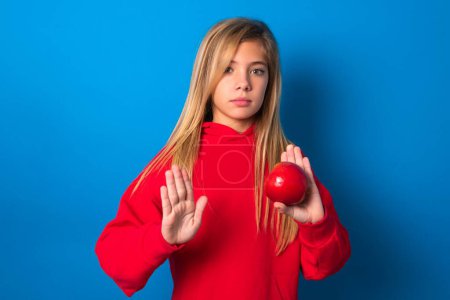 Photo for Beautiful caucasian teen girl wearing red sweater over blue wall doing stop sing with palm of the hand. Warning expression with negative and serious gesture on the face. - Royalty Free Image