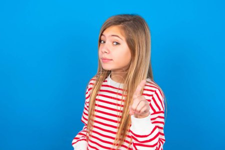 Photo for No sign gesture. Closeup portrait unhappy beautiful caucasian teen girl wearing striped shirt over blue studio background raising fore finger up saying no. Negative emotions facial expressions, feelings. - Royalty Free Image