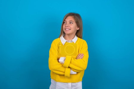 Foto de Sueño descanso relajado chica adolescente caucásica con suéter amarillo sobre la pared azul cruzando brazos, se ve bien copyspace - Imagen libre de derechos