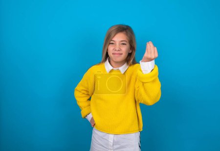 Téléchargez les photos : Caucasien adolescent fille porter jaune pull sur bleu mur en colère geste typique italien avec la main, regardant à la caméra - en image libre de droit