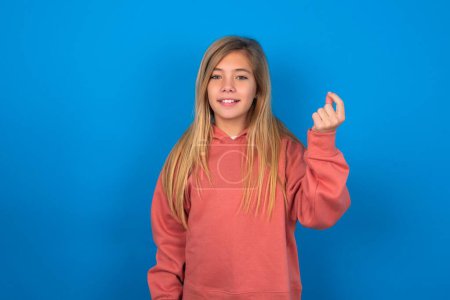Photo for Beautiful caucasian teen girl wearing pink sweater over blue wall pointing up with hand showing up seven fingers gesture in Chinese sign language Q. - Royalty Free Image