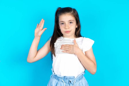 Photo for Beautiful caucasian kid girl standing over blue studio background Swearing with hand on chest and open palm, making a loyalty promise oath - Royalty Free Image