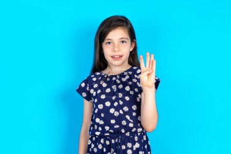 Téléchargez les photos : Belle fille enfant portant robe sur fond bleu montrant et pointant vers le haut avec les doigts numéro quatre tout en souriant confiant et heureux. - en image libre de droit