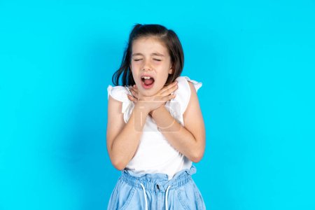 Photo for Beautiful caucasian kid girl standing over blue studio background shouting suffocate because painful strangle. Health problem. Asphyxiate and suicide concept. - Royalty Free Image