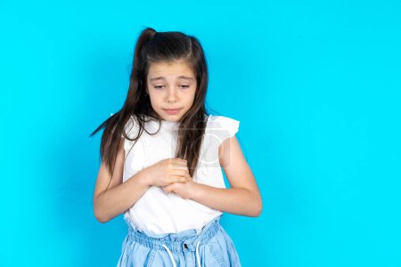 Photo for Sad kid desperate and depressed with tears on her eyes suffering pain and depression  in sadness facial expression and emotion concept. Beautiful caucasian little girl posing over blue studio background - Royalty Free Image