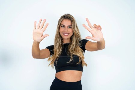 Photo for Young caucasian woman wearing sports clothes  showing and pointing up with fingers number eight while smiling confident and happy. - Royalty Free Image