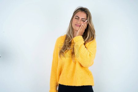 Foto de Joven mujer caucásica vistiendo suéter amarillo con dolor de muelas, disparo de estudio - Imagen libre de derechos