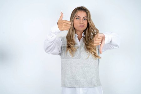 Photo for Caucasian woman wearing white shirt showing thumbs up and thumbs down, difficult choose concept - Royalty Free Image