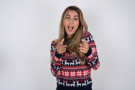 Foto de Mujer caucásica con suéter de Navidad dirige los dedos a la cámara selecciona a alguien. Te recomiendo. La mejor opción - Imagen libre de derechos