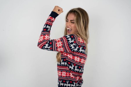 Téléchargez les photos : Photo de profil de femme caucasienne portant un pull de Noël soutenant l'équipe de football lever le poing en criant - en image libre de droit