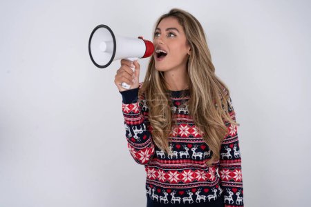 Photo for Funny caucasian woman wearing christmas sweater.People sincere emotions lifestyle concept. Mock up copy space. Screaming in megaphone. - Royalty Free Image