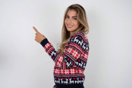 Foto de Foto de perfil de mujer caucásica con suéter de Navidad indican dedo vacío espacio oferta - Imagen libre de derechos