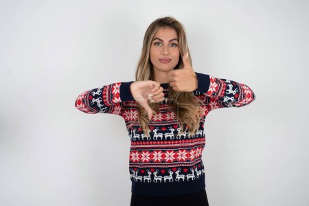 Foto de Mujer caucásica vistiendo suéter de Navidad mostrando el pulgar hacia abajo signo - Imagen libre de derechos