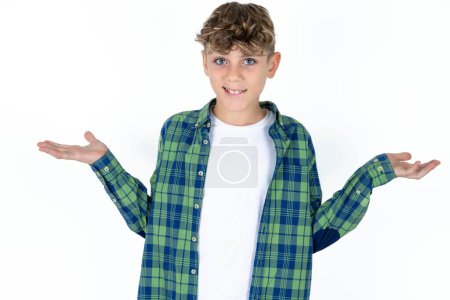 Photo for Clueless handsome caucasian teenager boy on white studio background shrugs shoulders with hesitation, faces doubtful situation, spreads palms, Hard decision - Royalty Free Image