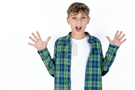 Photo for Optimistic handsome caucasian teenager boy on white studio background raises palms from joy, happy to receive awesome present from someone, shouts loudly, - Royalty Free Image