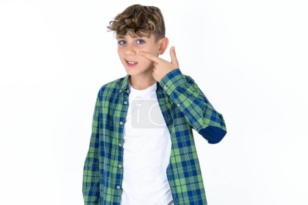 handsome caucasian teenager boy on white studio background pointing unhappy to pimple on forehead, ugly infection of blackhead. Acne and skin problem