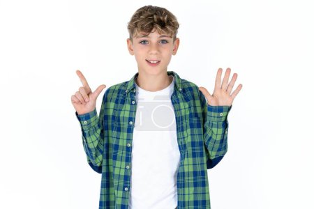 Foto de Guapo caucásico adolescente chico en blanco estudio fondo mostrando y apuntando hacia arriba con los dedos número siete mientras sonríe confiado y feliz. - Imagen libre de derechos