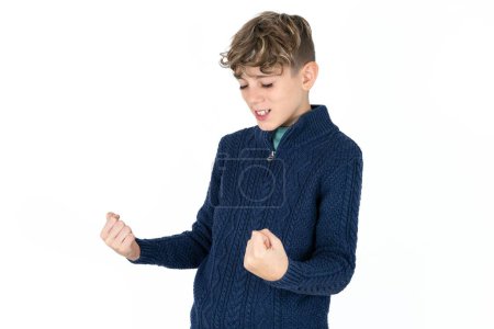 Téléchargez les photos : Beau garçon adolescent caucasien sur fond de studio blanc très heureux et excité de faire geste gagnant avec les bras levés, souriant et criant pour le succès. Concept de célébration. - en image libre de droit