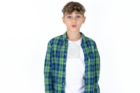 Photo for Shot of pleasant looking handsome caucasian teenager boy on white studio background pouts lips, looks at camera, Human facial expressions - Royalty Free Image