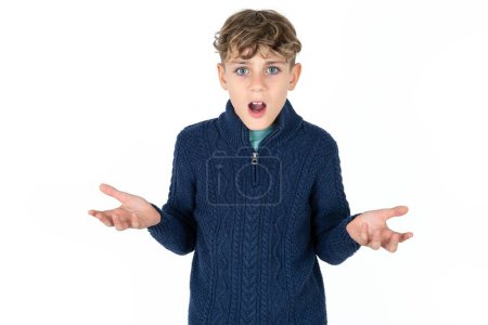 Photo for Frustrated handsome caucasian teenager boy on white studio background feels puzzled and hesitant, shrugs shoulders in bewilderment, keeps mouth widely opened, doesn't know what to do. - Royalty Free Image