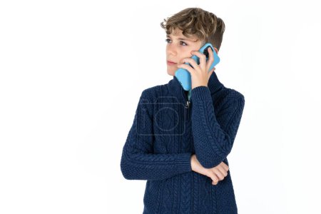 Téléchargez les photos : Triste adolescent caucasien beau garçon sur fond de studio blanc parlant sur smartphone. Concept de communication. - en image libre de droit