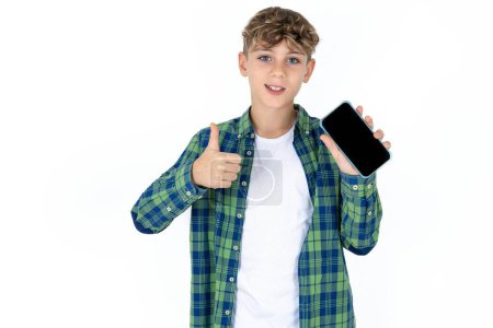 Photo for Portrait handsome caucasian teenager boy on white studio background holding in hands cell showing giving black screen thumb up - Royalty Free Image