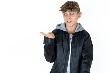Foto de Guapo caucásico adolescente chico en blanco estudio fondo puntos de distancia y da consejos demuestra publicidad - Imagen libre de derechos