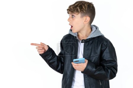 Photo for Stunned handsome caucasian teenager boy on white studio background points sideways right copy space, recommends product, sees astonishing thing - Royalty Free Image