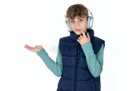 Foto de Positivo guapo caucásico adolescente chico en blanco estudio fondo anuncio promo tacto dedo dientes - Imagen libre de derechos