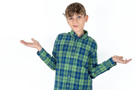 Foto de Descuidado atractivo guapo caucásico adolescente chico en blanco estudio fondo encogiéndose de hombros, oops. - Imagen libre de derechos