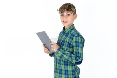 Foto de Foto de optimista guapo caucásico adolescente chico en blanco estudio de fondo celebrar tableta - Imagen libre de derechos