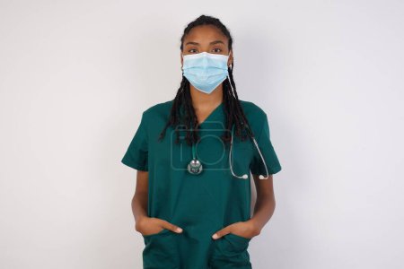 Photo for Confidence and business concept. Portrait of charming successful young doctor woman, smiling broadly with self-assured expression while holding hands in pockets. - Royalty Free Image