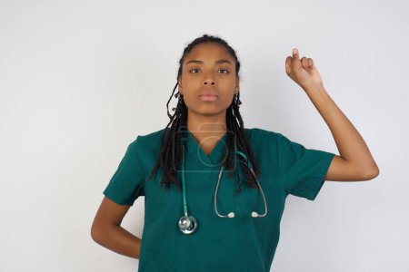 Photo for Young pretty doctor woman feeling serious, strong and rebellious, raising fist up, protesting or fighting for revolution against grey wall. - Royalty Free Image