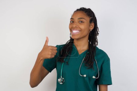 Téléchargez les photos : Beau travail ! Portrait d'une jeune femme médecin heureuse et souriante donnant le pouce vers le haut geste debout à l'extérieur. Émotion humaine positive expression faciale langage corporel. Fille drôle - en image libre de droit