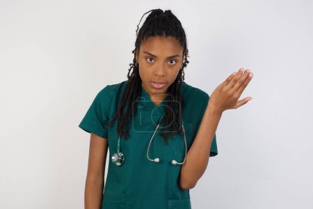 Téléchargez les photos : What the hell are you talking about, nonsense. Studio shot of frustrated doctor female gesturing with raised palm, frowning, being displeased and confused with dumb question over gray wall. - en image libre de droit