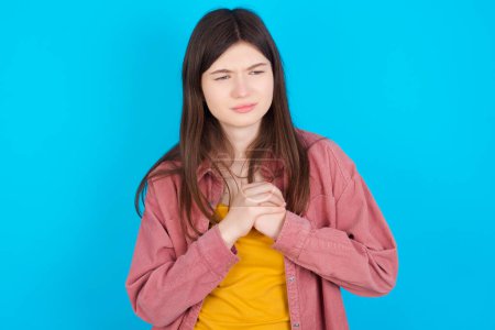 Photo for Sad young caucasian girl wearing pink shirt isolated over blue background feeling upset while spending time at home alone staring at camera with unhappy or regretful look. - Royalty Free Image