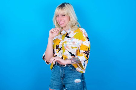 Photo for Ugh how disgusting! Displeased Caucasian girl wearing floral shirt isolated over blue background , has dissatisfied facial expression as sees something abominable. - Royalty Free Image