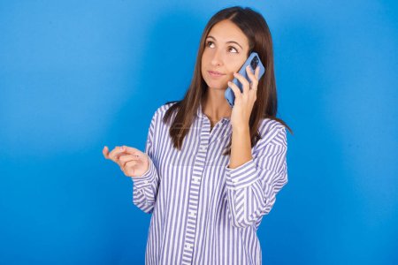 Foto de Hermosa mujer joven habla en el teléfono móvil pasa tiempo libre en interiores llamadas a un amigo. - Imagen libre de derechos
