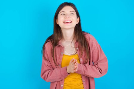 young woman over blue background feeling happy, smiling and clapping hands, saying congratulations with an applause.