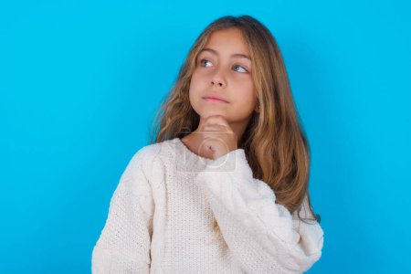 Photo for Thoughtful pretty teen girl holds chin and looks away pensively makes up great plan - Royalty Free Image