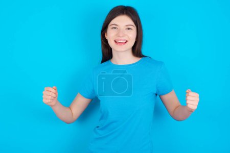 Photo for Happy young caucasian girl wearing blue T-shirt isolated over blue background Holding Empty Paper Board Advertising Offer Text Standing. Autumn Advertisement Banner. - Royalty Free Image