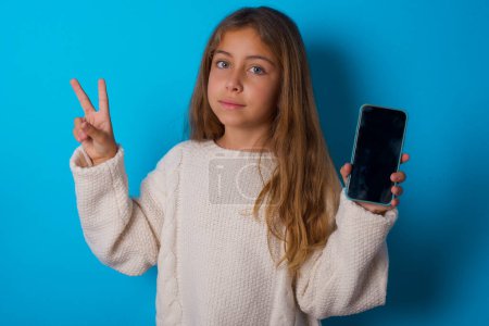 Photo for Pretty teen girl holding modern device showing v-sign - Royalty Free Image