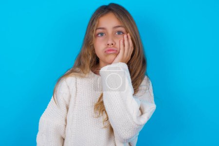 Photo for Sad lonely pretty teen girl touches cheek with hand bites lower lip and gazes with displeasure. Bad emotions - Royalty Free Image