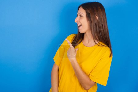 Happy cheerful smiling Young woman looking and pointing aside with hand. Copy space and advertisement concept.