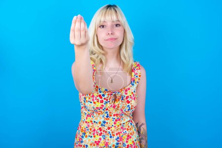 Photo for Caucasian girl wearing floral dress isolated over blue background Doing Italian gesture with hand and fingers confident expression - Royalty Free Image