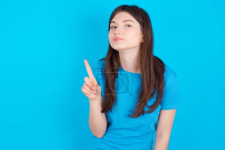 Photo for No sign gesture. Closeup portrait unhappy young caucasian girl wearing blue T-shirt isolated over blue background raising fore finger up saying no. Negative emotions facial expressions, feelings. - Royalty Free Image