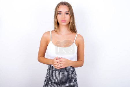 Photo for Business Concept - Portrait of Young Caucasian girl wearing white tank top on white background holding hands with confident face. - Royalty Free Image