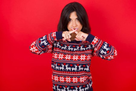 Photo for Brunette caucasian woman wearing christmas sweater over red background Has rejection angry expression crossing fingers doing negative sign. - Royalty Free Image