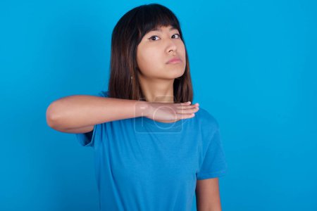 Photo for Young asian woman wearing blue t-shirt against blue background cutting throat with hand as knife, threaten aggression with furious violence. - Royalty Free Image