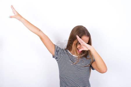 Photo of funky beautiful blonde girl wearing striped t-shirt on white background show disco move dab